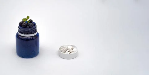 Blue bottle with vitamin berries pills concept. on white background Stock Photos