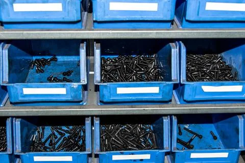 Blue box with small construction storage compartments filled with screws, nut Stock Photos