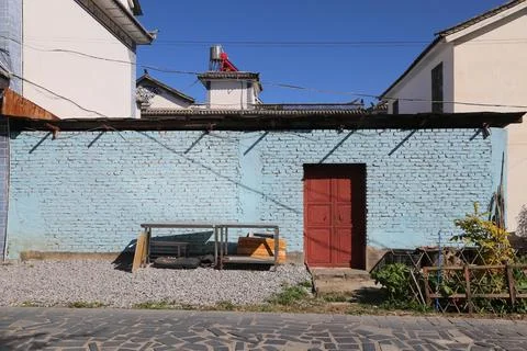 Blue brick wall with red double doors under clear sky Stock-Fotos