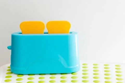 Blue bright toaster with bread on a bright dotted table on a white plate Stock Photos
