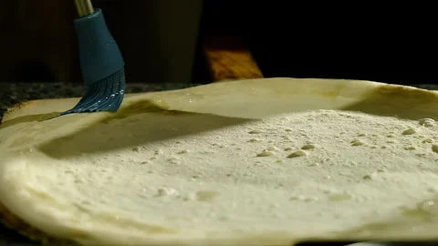 Blue brush strokes as cook oils pizza dough before baking Stock Footage 325069966