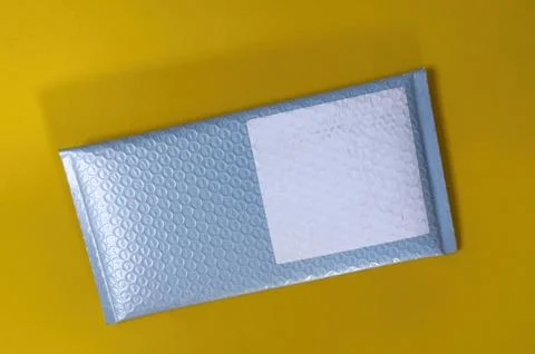 Blue Bubble Mailer on Yellow Background Stock Photos