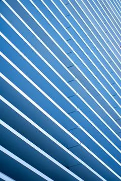 Blue building facade displaying abstract diagonal lines and geometric patterns Stock Photos