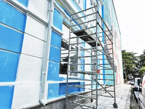 Blue Building Facade Under Construction With Scaffolding On A Busy City Stock Photos