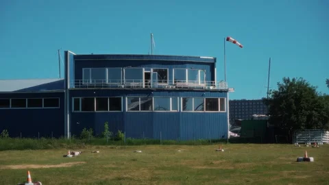 Blue building with large windows and balcony, surrounded by green grass and wind Stock Footage 328480846