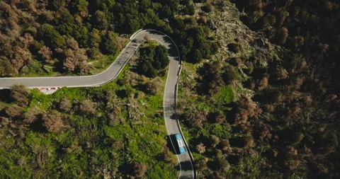 Blue bus turns left on a mountain road aerial view. Dangerous narrow forest Stock Footage 86203151