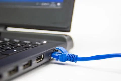 Blue cable network connection to a Lan port of laptop computer on white table Stock Photos