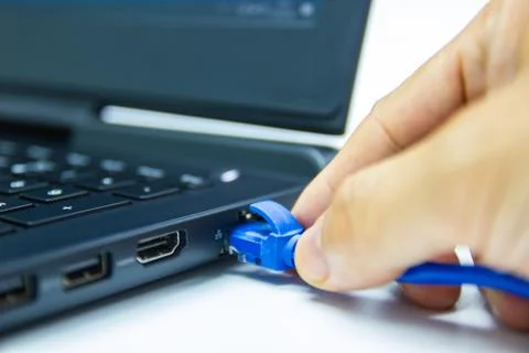 Blue cable network connection to a Lan port of laptop computer on white table Photos