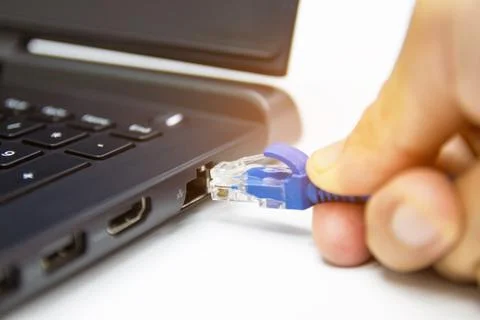 Blue cable network connection to a Lan port of laptop computer on white table Stock Photos