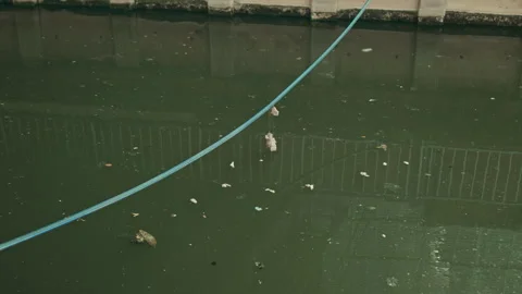 Blue Cable Stretched Across Murky City Canal with Water Ripples and Wind Stock Footage 330516407