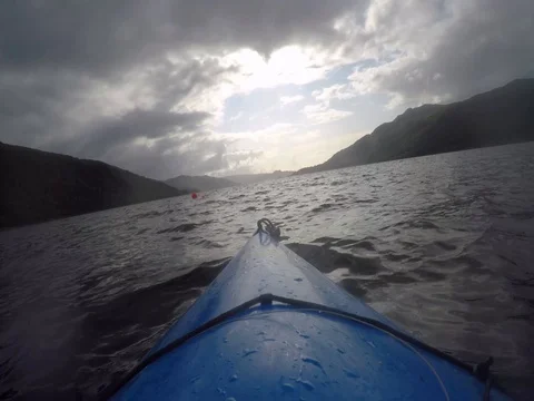 Blue Canoe Splices through the waters of a Scottish loch under an ominous, 動画素材 79884944