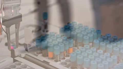 A blue-capped test tube being taken out of a tray by a robotic arm and put on a Stock Footage 232491063