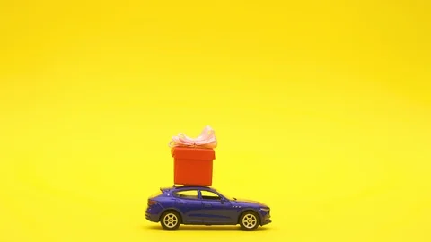 Blue car drive red present on roof on yellow background - Stop motion Stock Footage 125497754