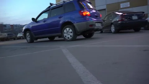 A blue car is moving fast in the parking lot in the evening close-up. Drive from Stock-Footage 153206838