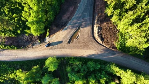 Blue car on a rural road fork junction surrounded by lush green trees Vídeos de archivo 341398606