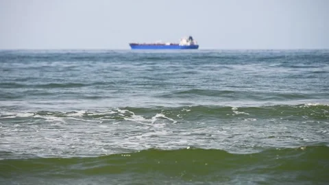 Blue cargo ship sailing calm sea with rolling waves under clear sky horizon Stock Footage 344329820