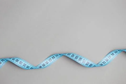 Blue centimeter ribbon on a gray background, the concept of fitness and weight Stock Photos