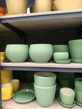 Blue ceramic planters with saucers in assorted sizes arranged on shelves in.. 스톡 사진