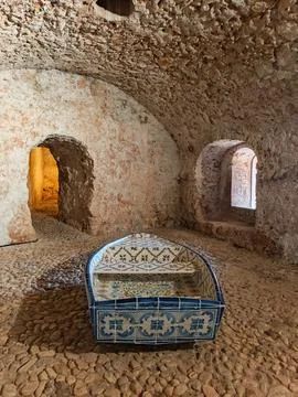 Blue ceramic tiled bed in rustic stone cellar interior Фото