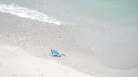 Blue Chair on Sandy Beach, A Tranquil Seating Spot Stock-Footage 262395563