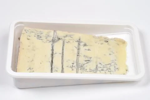 Blue cheese slice inside a white plastic container side angle view Stock Photos
