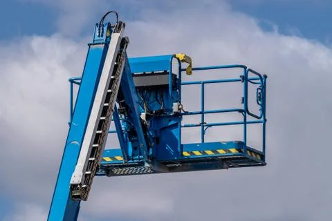 Blue cherry picker machine against blue sky background Stock Photos