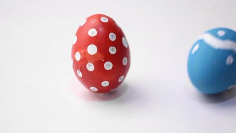 Blue chicken egg with dotted and zigzag pattern hits red egg with polka dots Stock Footage 297207113