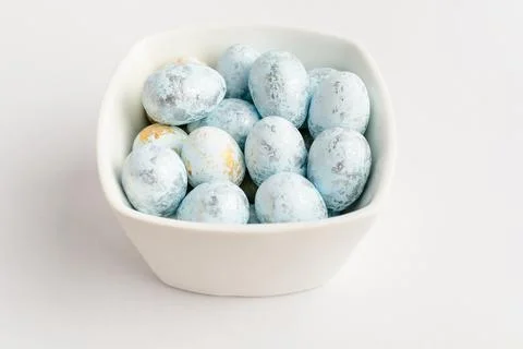 Blue chocolate coated Easter eggs candies on a bowl isolated on a white table Stock Photos