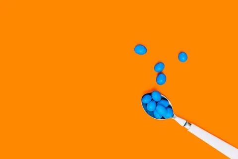 Blue chocolates inside a white spoon on an orange background. wallpaper to use Stock Photos