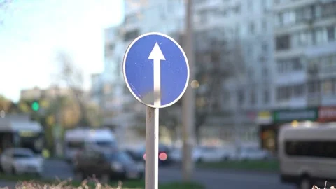 Blue circular mandatory direction sign with white upward arrow on city street Vídeos de archivo 348431060