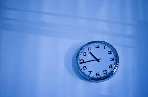 Blue clock on a blue wall Stock Photos