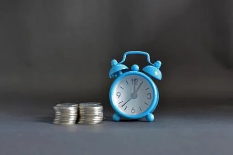Blue clock with silver coin Stock Photos