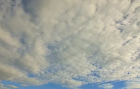A blue cloudy sky with many small clouds blocking the sun Stock Photos
