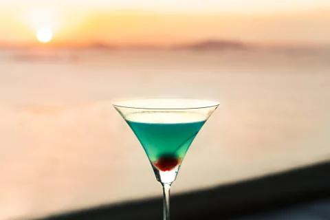Blue cocktail with cherry on window view of sunset Stock Photos