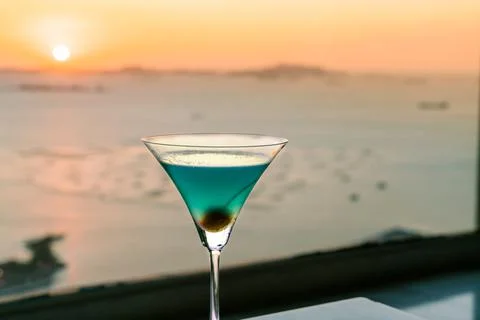 Blue cocktail with cherry on window view of sunset Stock Photos