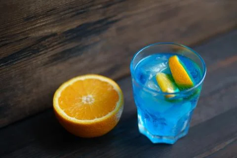 Blue cocktail with orange slice and ice cubes Stock Photos
