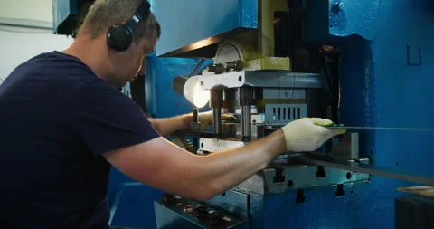 Blue collar machine operator handling metal parts at industrial press Stock Footage 336851141