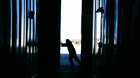 Blue Collar Worker Opening Hangar Gate Inside Industrial Warehouse, Backlit - 4K Stock Footage 217398496