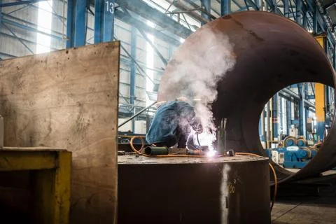 Blue-collar worker welding in the interior of a factory Stock Photos