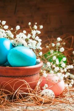 Blue colored Easter eggs and quail eggs in a clay bowl on the old wooden back Stock Photos