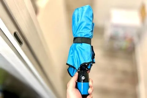 Blue compact umbrella in a hand. Stock Photos