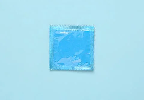 Blue condom in a small packet on light blue background 写真素材