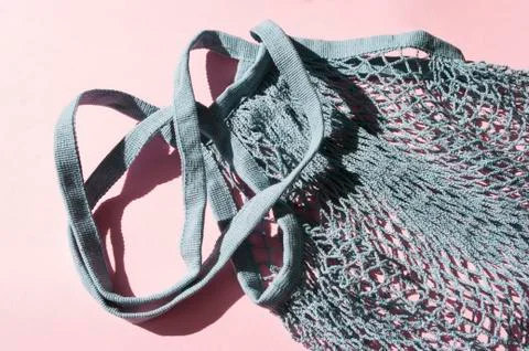Blue cotton string knitted bag on pink background. Top view, flat lay. Zero w Stock Photos