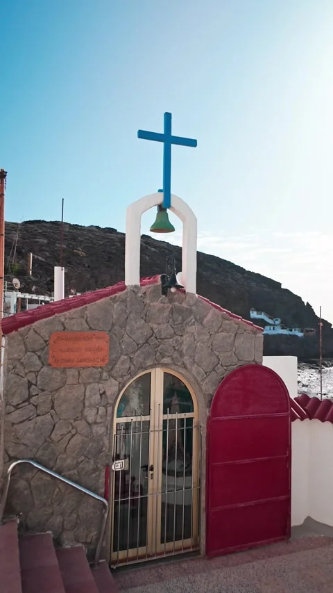 Blue cross over small seaside chapel with a blue sky Stock Footage 294278838