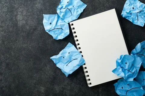 Blue crumpled sticky notes blank with drawing sad face on black background wi Foto stock