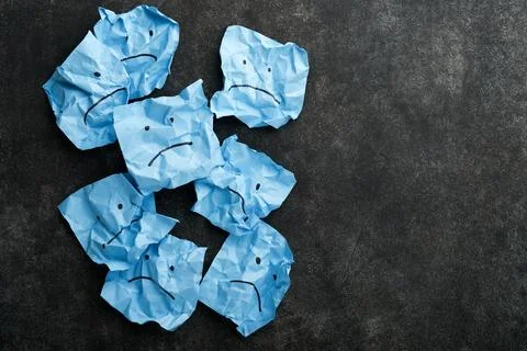 Blue crumpled sticky notes blank with drawing sad face on black background wi Foto stock