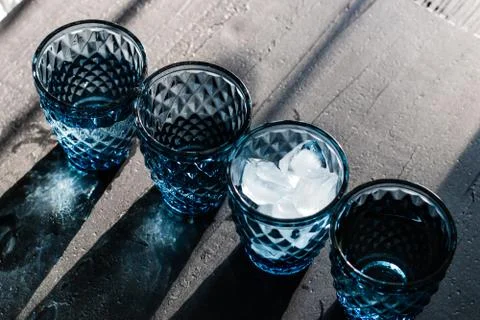 Blue crystal glasses of geometric pattern with ice and drinks in diagonal lin Stock Photos