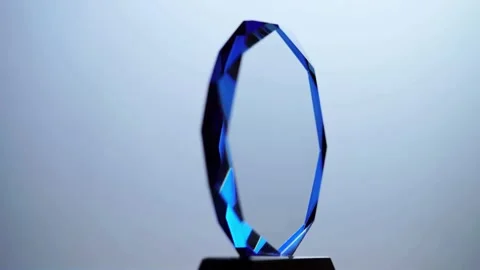 A blue crystal trophy rotates slowly on black base Stock Footage 333810790