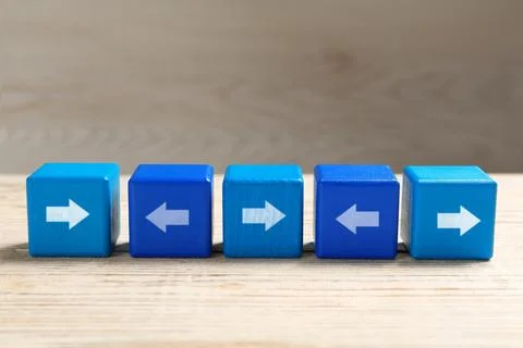 Blue cubes with arrows pointing in different directions on wooden table Stock Photos