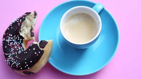 Blue cup of coffee with half bitten donut on rotating pink plate Stock Footage 73969007